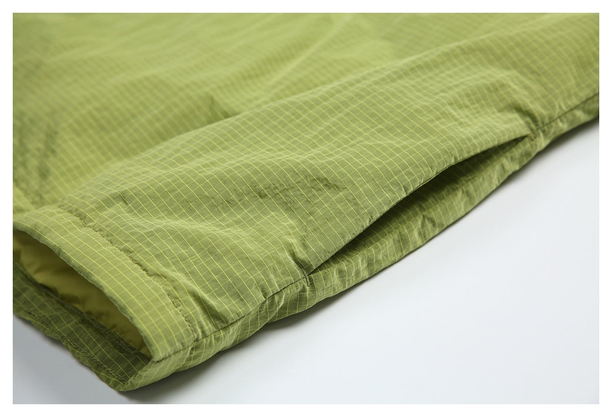Close-up of olive-green grid-patterned garment fabric showing a folded edge and stitched seam.