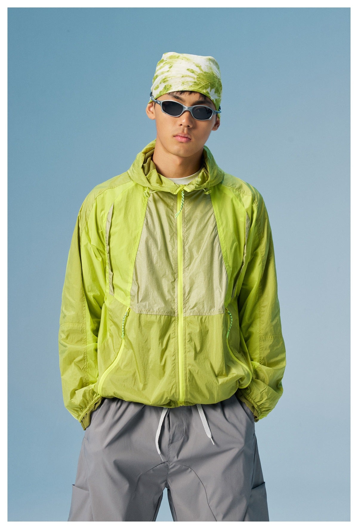 Front view of a model in a lime-green color-block hooded jacket with a center zip and drawcord pockets.