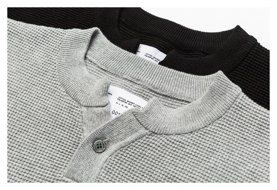 Close-up of gray and black knit tops, showing the gray ribbed collar, button placket, and inner labels.