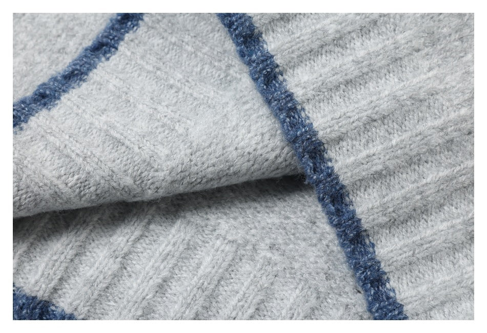 Close-up of folded light gray knit fabric with dark blue trim and visible stitches.