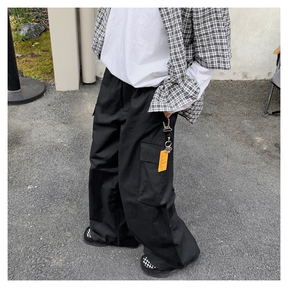 Close view of a person wearing black wide-leg cargo pants, highlighting a side flap pocket and hanging keychain.