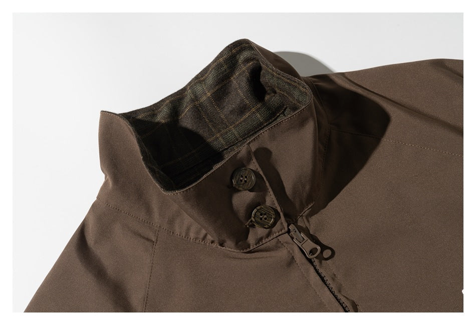 Close-up of a brown jacket collar with plaid lining, two buttons, and a front zipper.