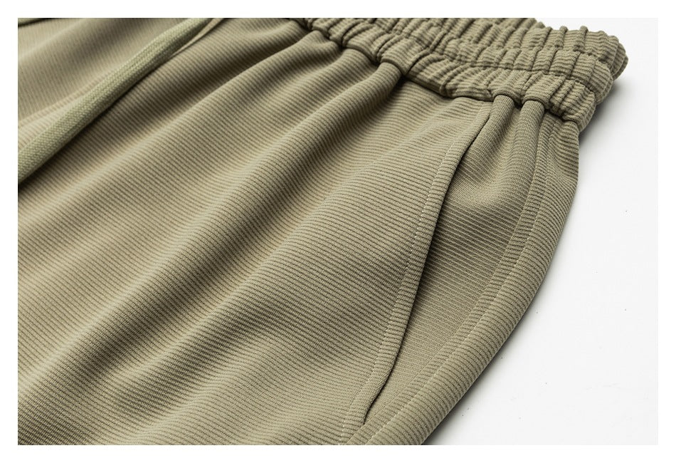 Close-up of olive-khaki pants showing a side pocket seam below the elastic waistband.