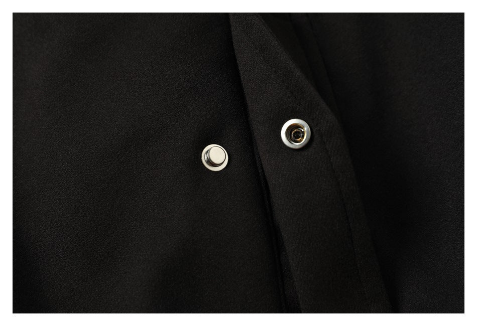 Close-up of two silver snap fastener components on black jacket fabric.