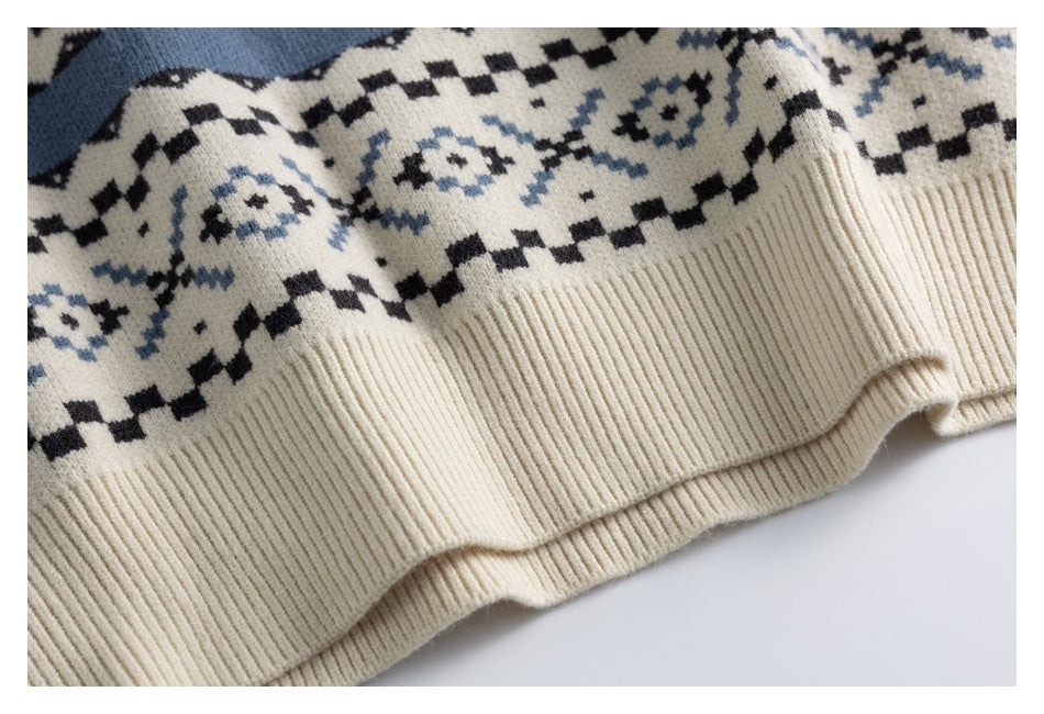 Close-up of an ivory sweater hem with ribbed trim and a black and dusty blue geometric pattern.