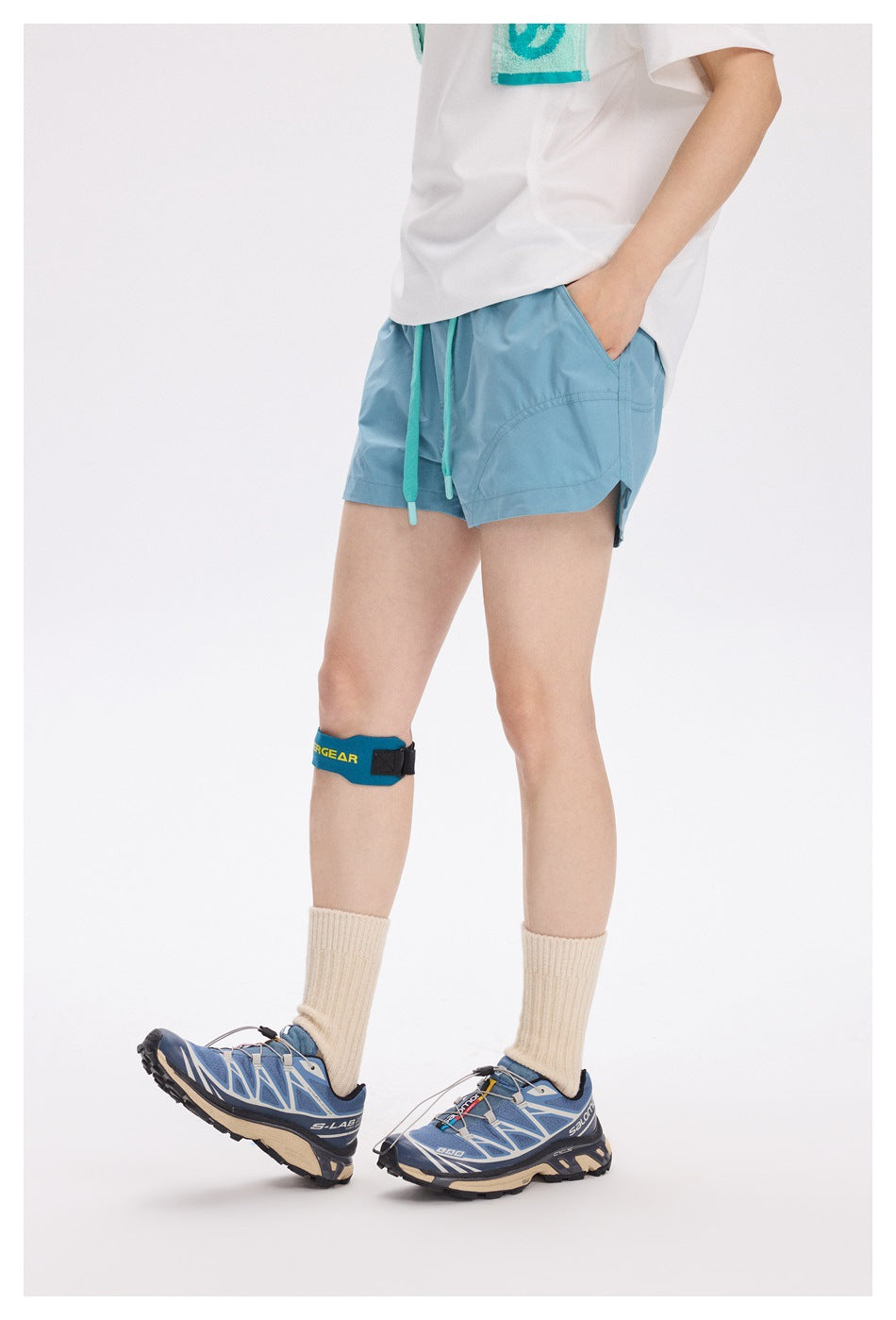 Side view of a model wearing light teal running shorts with turquoise drawstrings and a curved side panel.