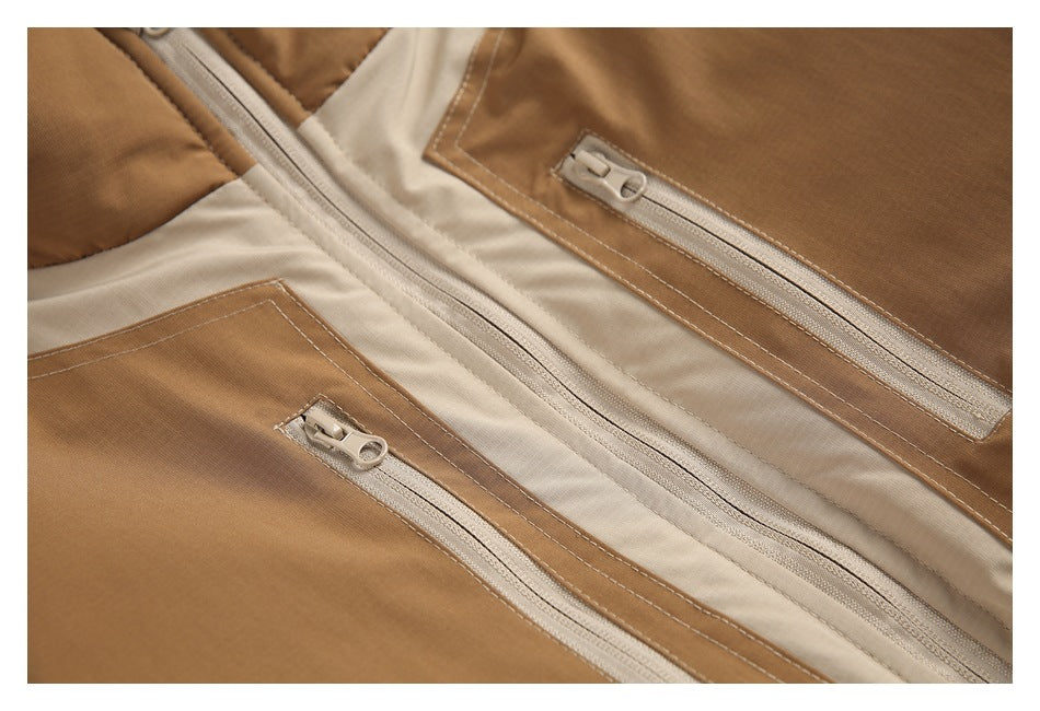 Close-up of a tan and cream jacket front with two zip pockets and a central zipper.