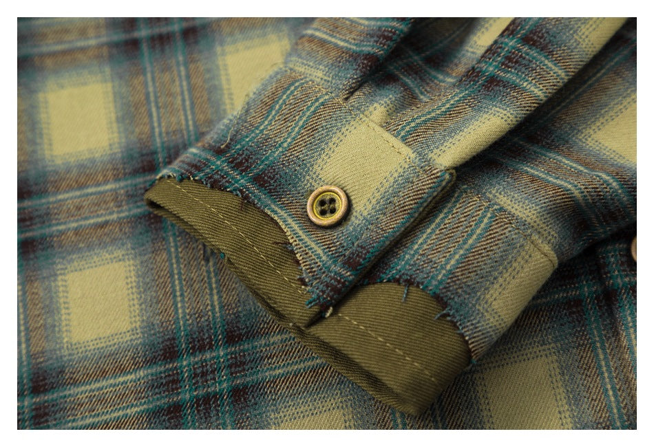 Close-up of a buttoned cuff on a tan, teal, and brown plaid shirt.