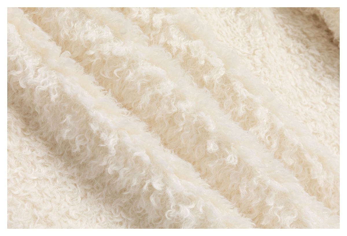 Extreme close-up showing the cream garment's dense curly-pile surface and raised folded edge.