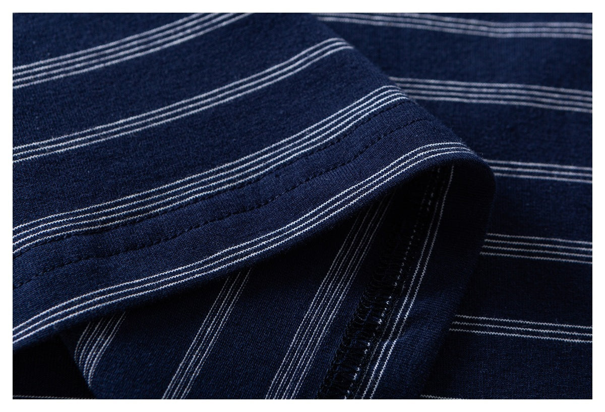 Close-up of a folded, stitched edge on navy fabric with thin white stripes.