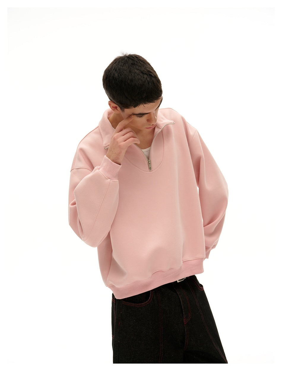 Close view of a model wearing a pale pink quarter-zip pullover, highlighting its collar, zipper and roomy sleeves.