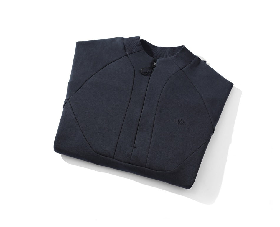 Folded dark navy pullover with a short front zipper, stand collar, curved seams, and small chest emblem.