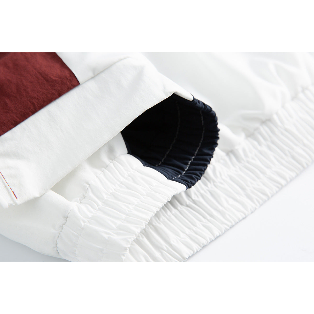 Close-up of a white jacket sleeve cuff with gathered elastic and a navy inner section.