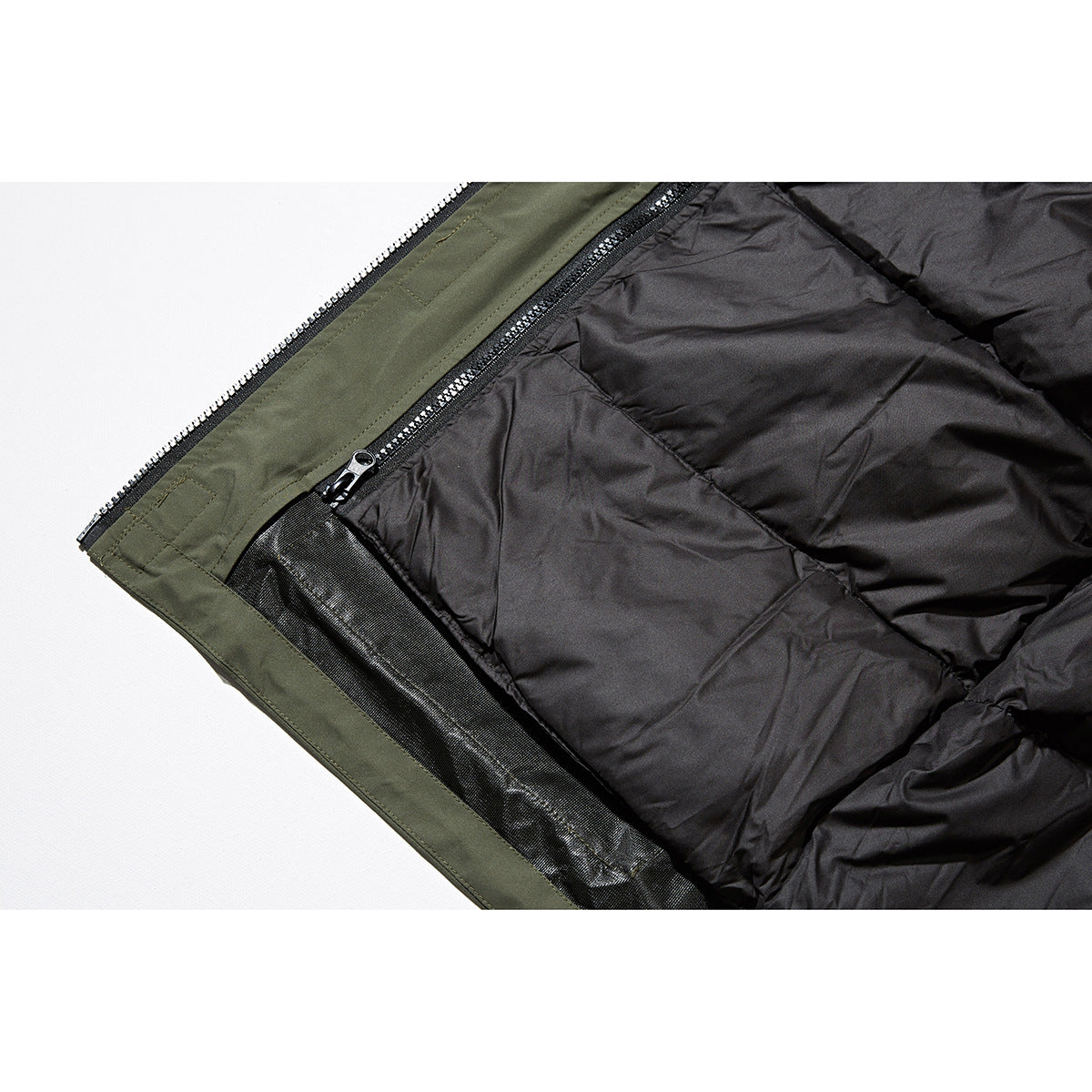Close-up of the jacket's black quilted interior lining and zipper beside the olive outer shell.