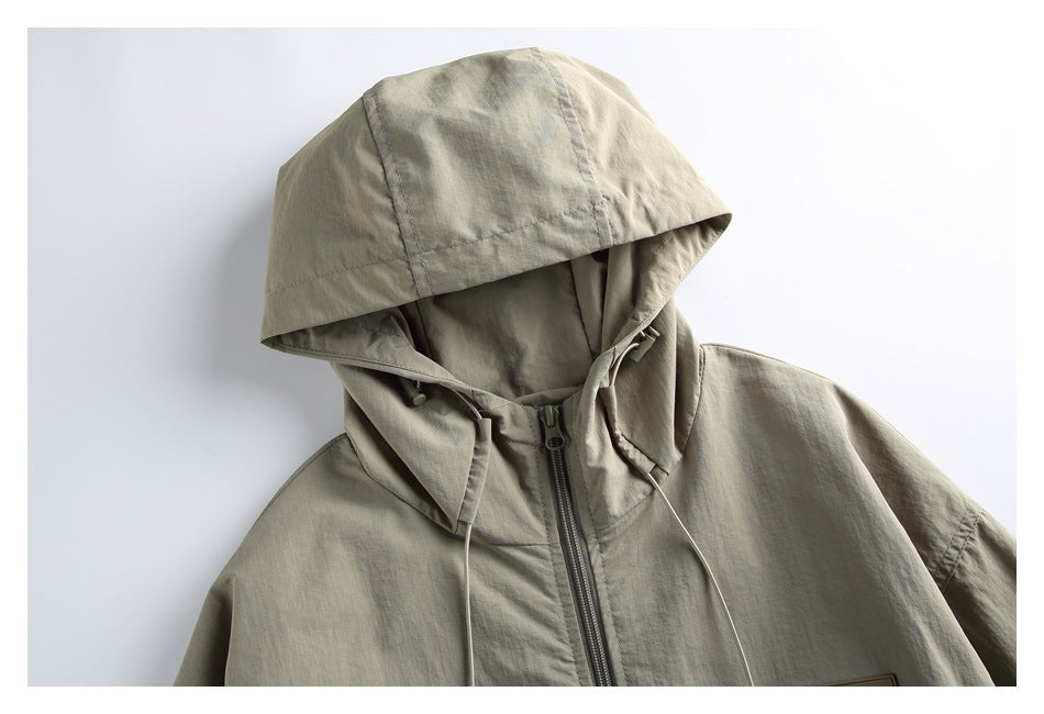 Close-up of an olive-gray hooded jacket showing the large hood, high collar, front zipper and drawcords.