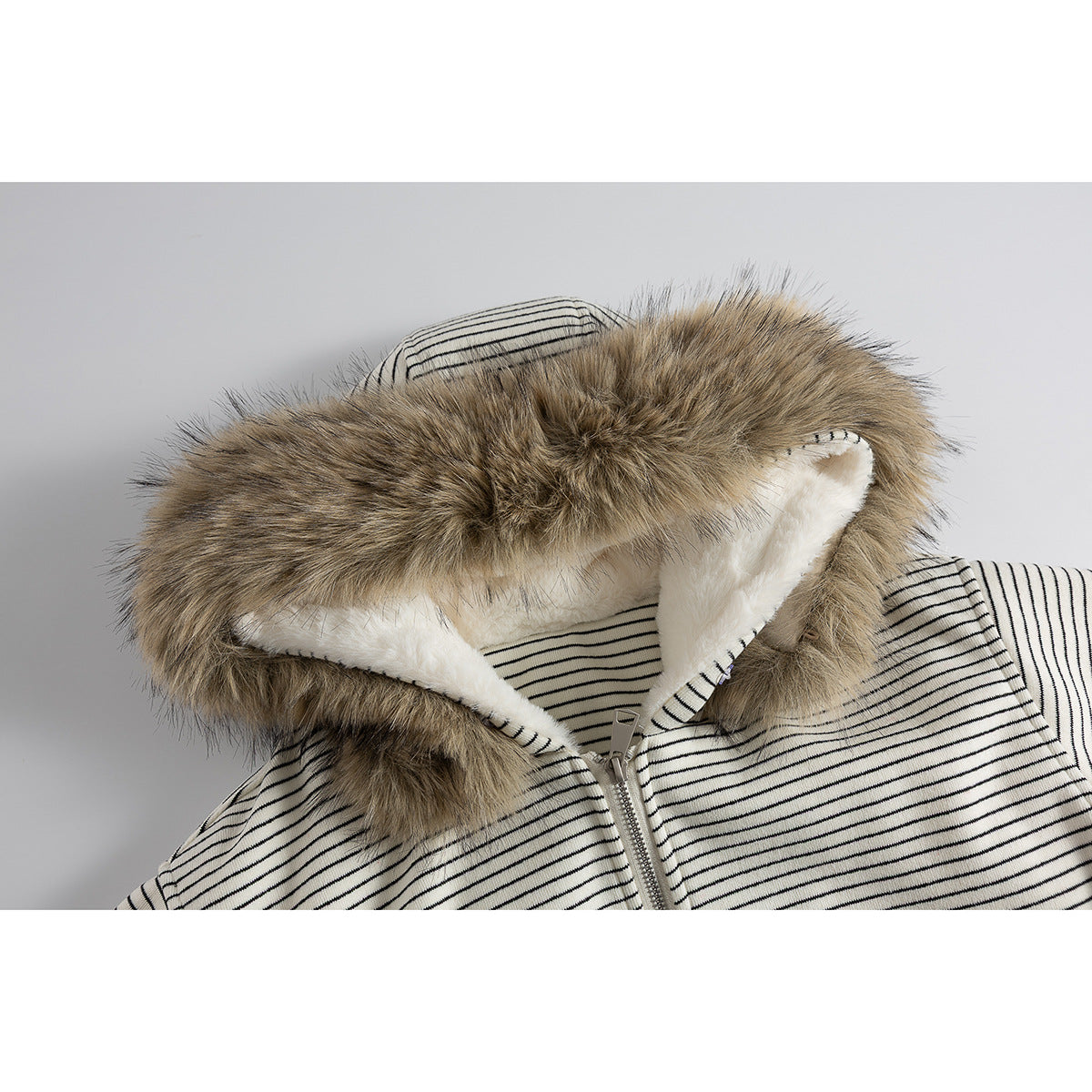 Close-up of a cream-and-black striped jacket hood with brown faux-fur trim, white lining, and a front zipper.