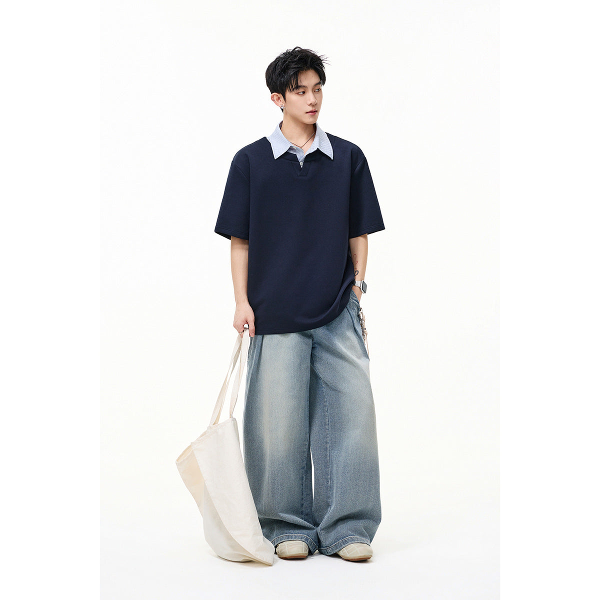 Model wearing a navy short-sleeve top with a pale striped collar and very wide light-wash jeans.