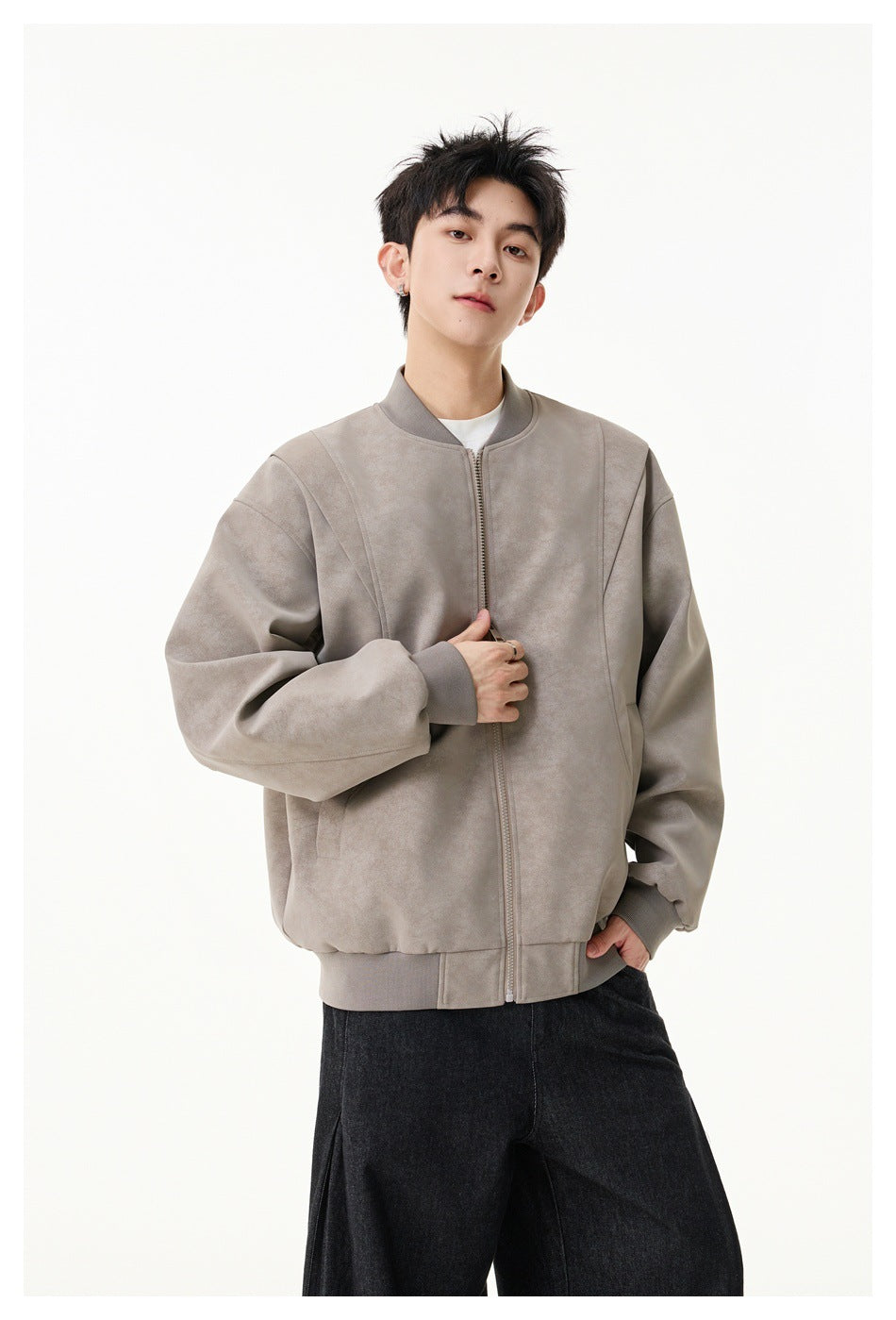 Model wearing a taupe zip-front bomber jacket with a stand collar, ribbed cuffs and hem, and black trousers.