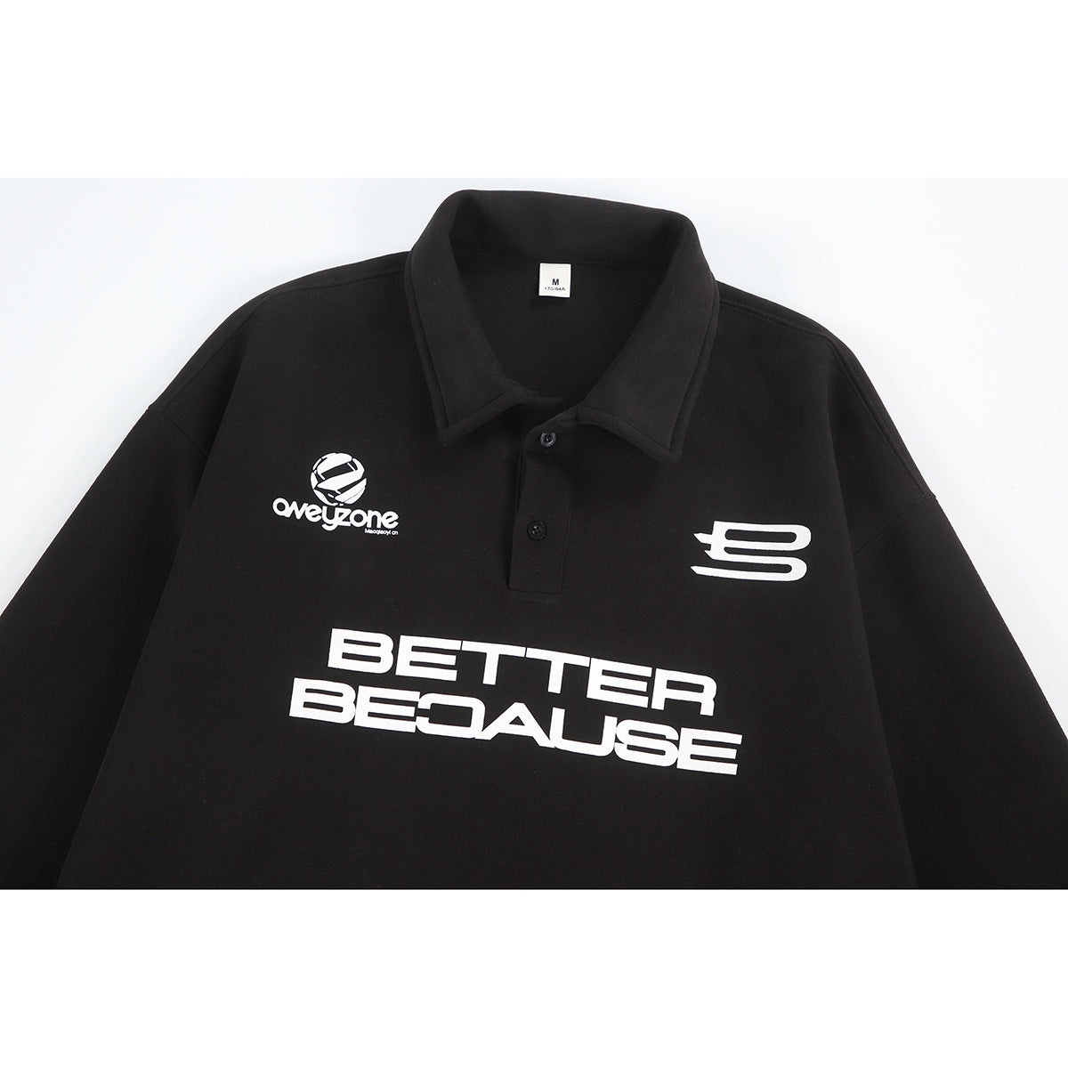 Black long-sleeve polo with a collar, white chest graphics, and large “BETTER BECAUSE” lettering.