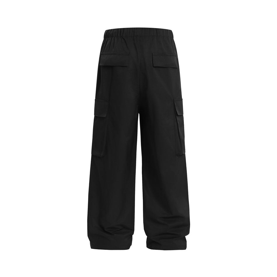 Back view of loose black cargo pants with an elastic waist, two rear flap pockets, and large side cargo pockets.