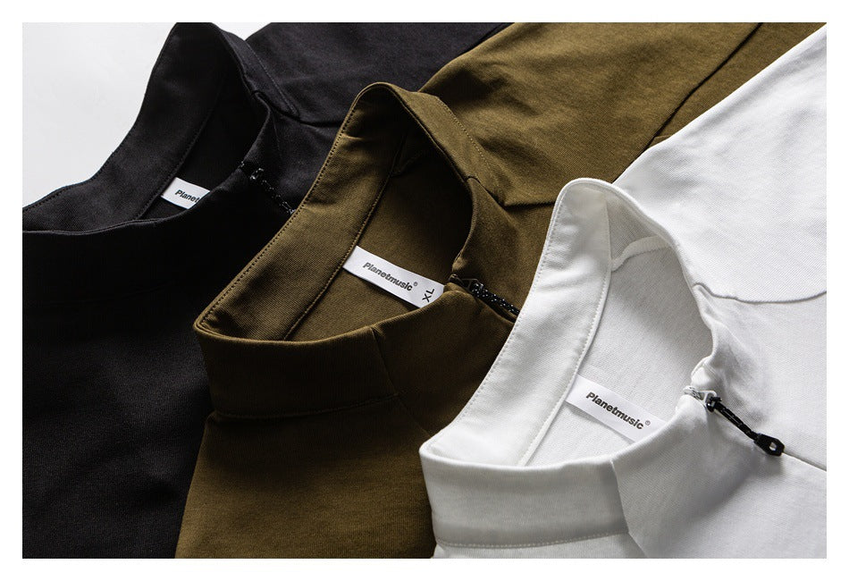 Close-up of black, olive-brown, and white tops showing their stand collars and short zippers.