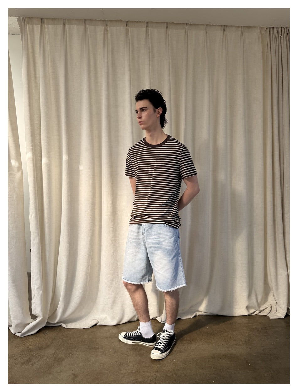 Full-length view of a model wearing a dark brown and cream striped short-sleeve T-shirt with light denim shorts.