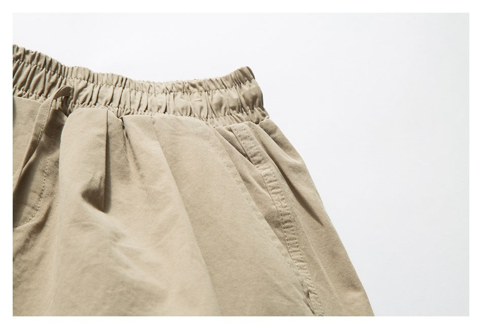 Close-up of beige shorts showing the gathered elastic waistband and stitching around a pocket.