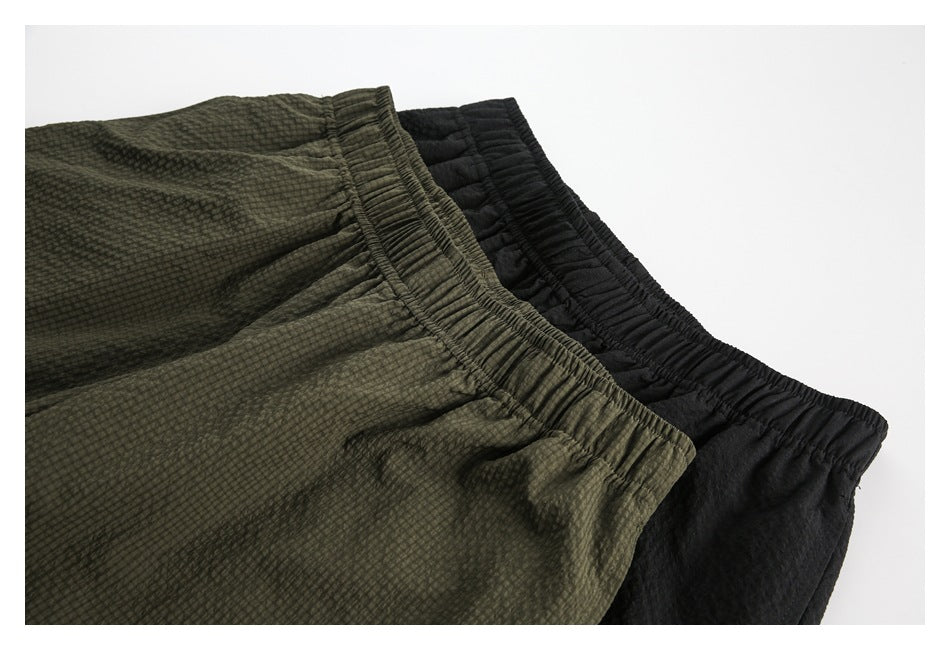 Close-up of olive and black shorts showing their gathered elastic waistbands and textured fabric.