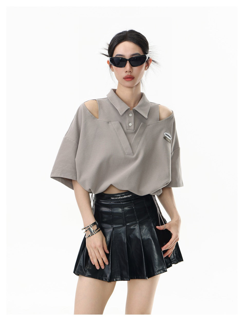 Front view of a model wearing a taupe cutout-shoulder polo top with a V-shaped front panel and drawstring hem.