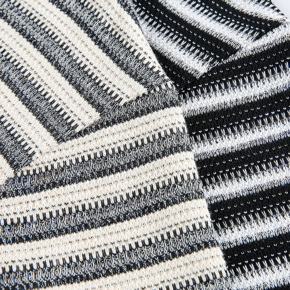 Close-up of black, gray, and cream striped knit fabric, showing the textured stitching and folded layers.
