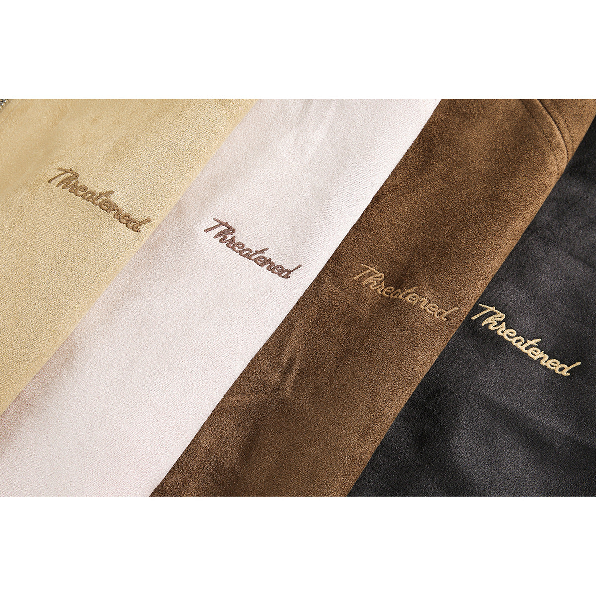 Close-up of embroidered script on tan, blush, brown, and black jacket fabric.