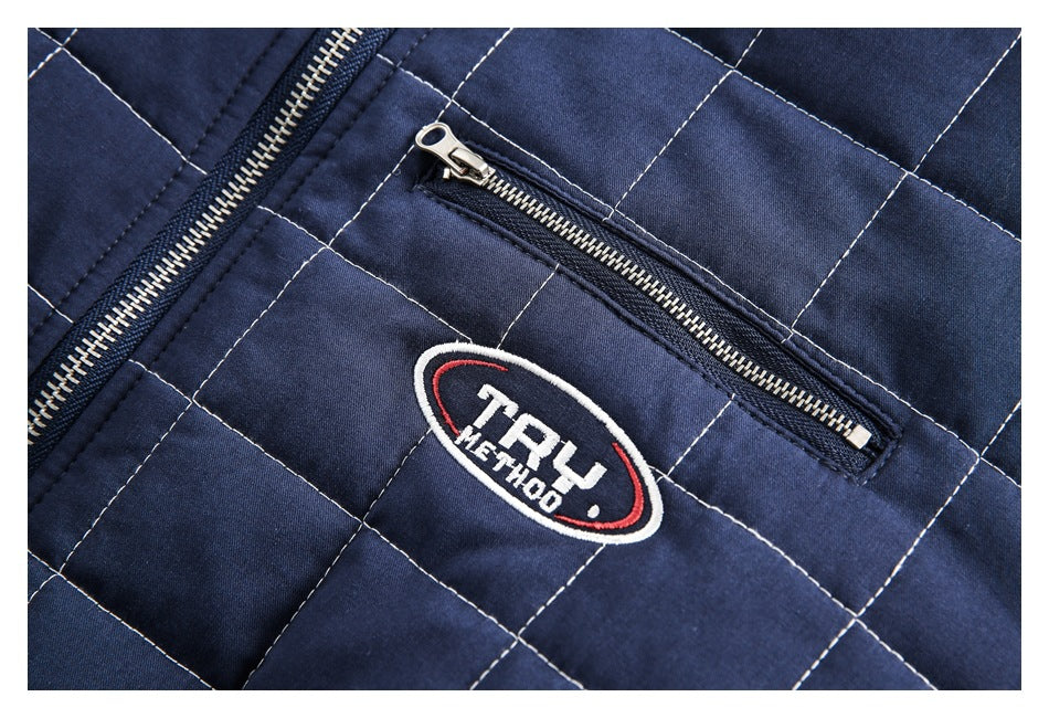 Close-up of navy quilted garment with light contrast stitching, metal zippers, and an embroidered oval logo.