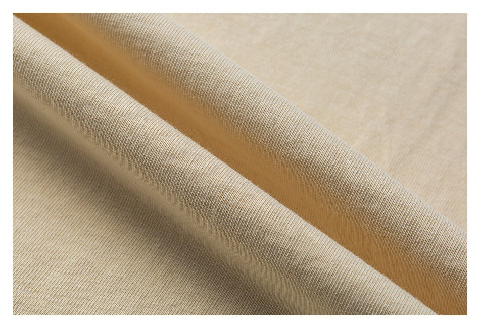 Close-up of light beige knit fabric draped in soft folds, showing its fine ribbed texture.