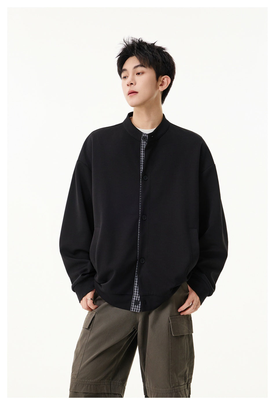 Model wears a black oversized stand-collar jacket with a checked button placket and side pockets.