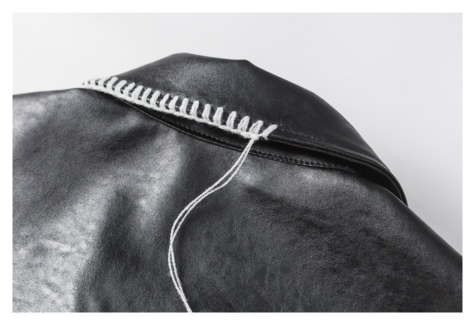 Close-up of a black jacket seam with thick white stitching and a loose thread.
