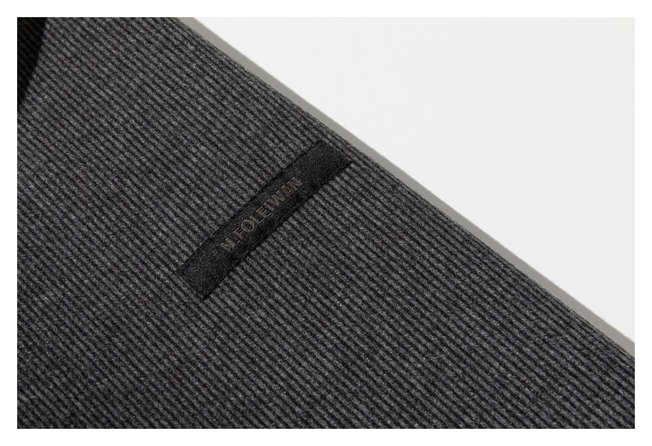 Close-up of a dark gray ribbed garment with a small black sewn label on the fabric.