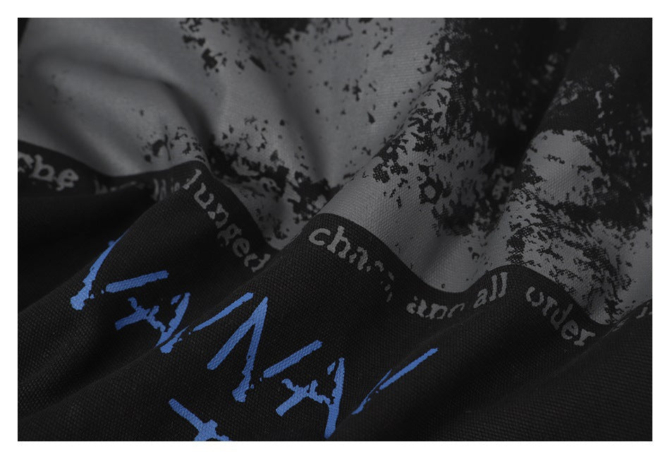 Close-up of black garment fabric with a gray abstract print and blue graphic lettering.