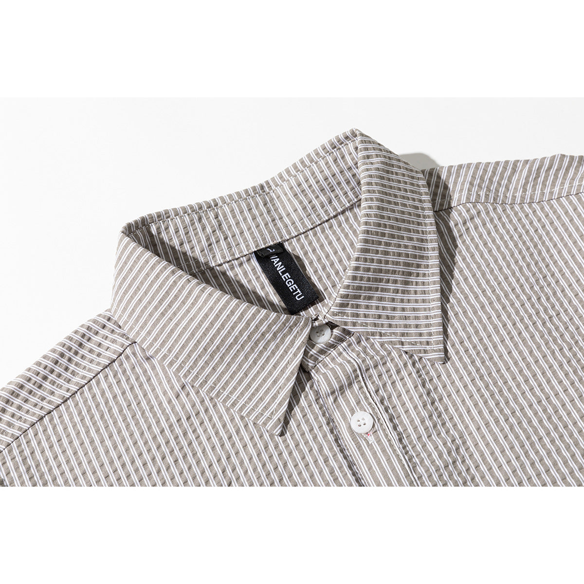 Close-up of a taupe-and-white striped shirt collar, placket, and white buttons.