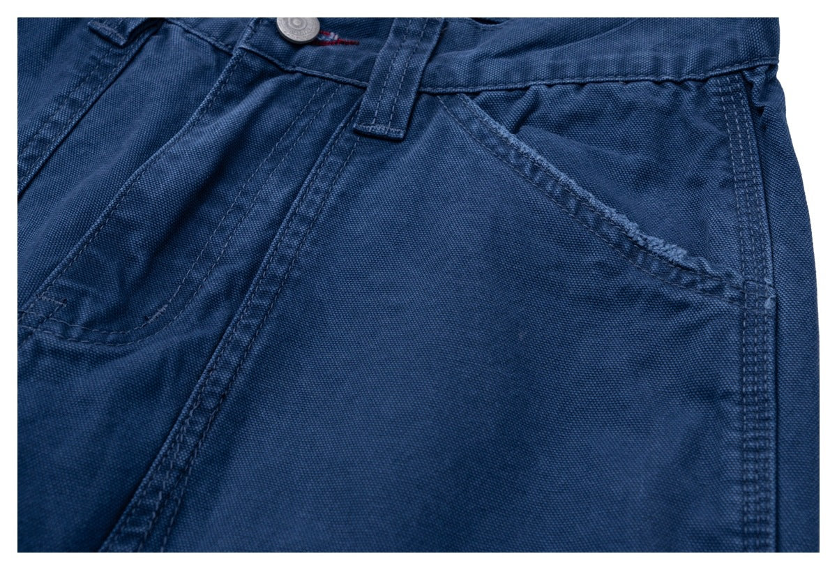 Close-up of dark blue trousers showing the front pocket opening, waistband and belt loop.