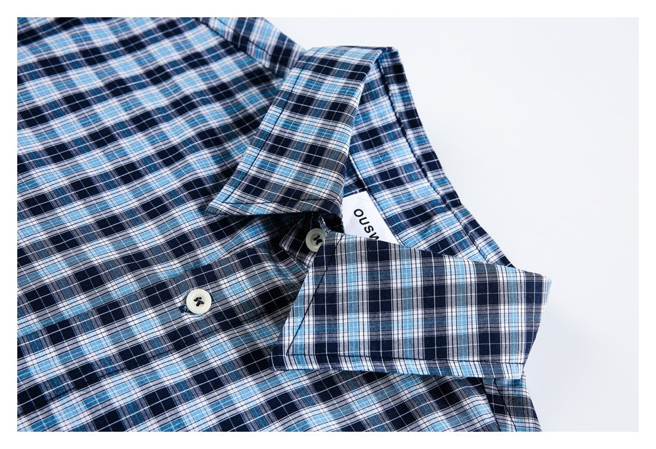 Close-up of a blue plaid shirt collar, button placket, and folded cuff.