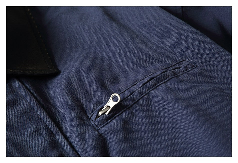 Close-up of a dark navy garment with a slanted zip pocket and silver zipper pull.