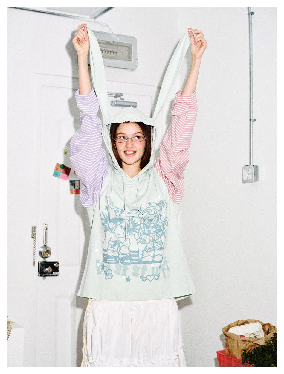 Model wearing the mint hoodie with striped sleeves, holding the long bunny-ear hood extensions up