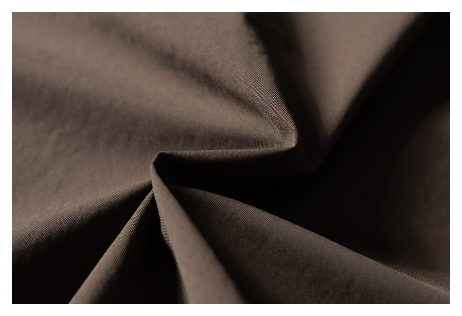 Macro close-up of dark brown jacket fabric arranged in folds.