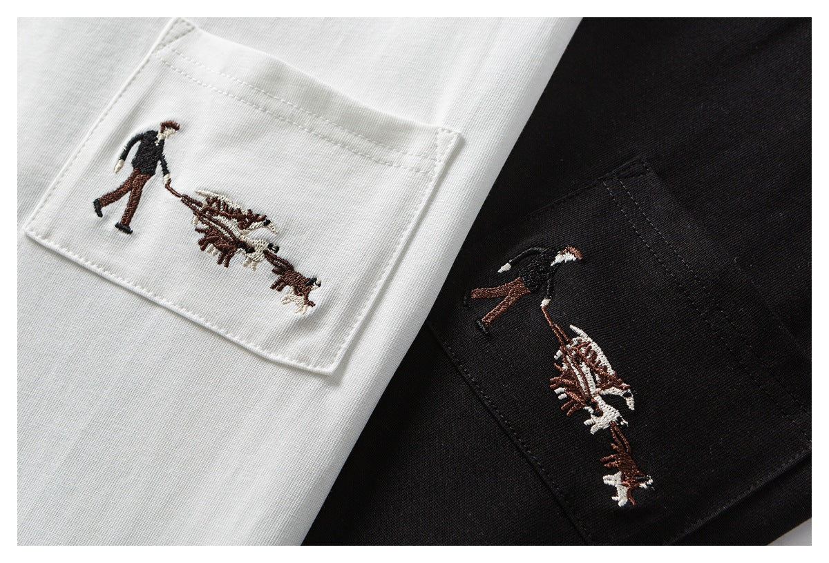 Close-up of white and black garments with pockets embroidered with a person walking dogs.