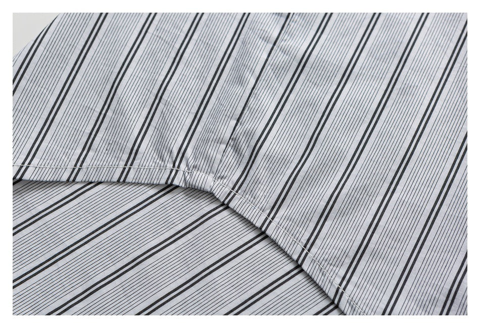 Close-up of light gray fabric with thin black stripes and a curved stitched seam.