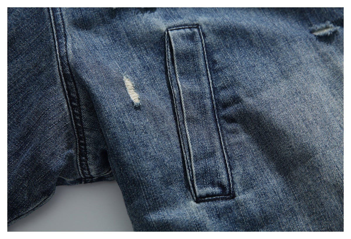 Close-up of a denim jacket pocket seam and small distressed detail on faded blue denim.
