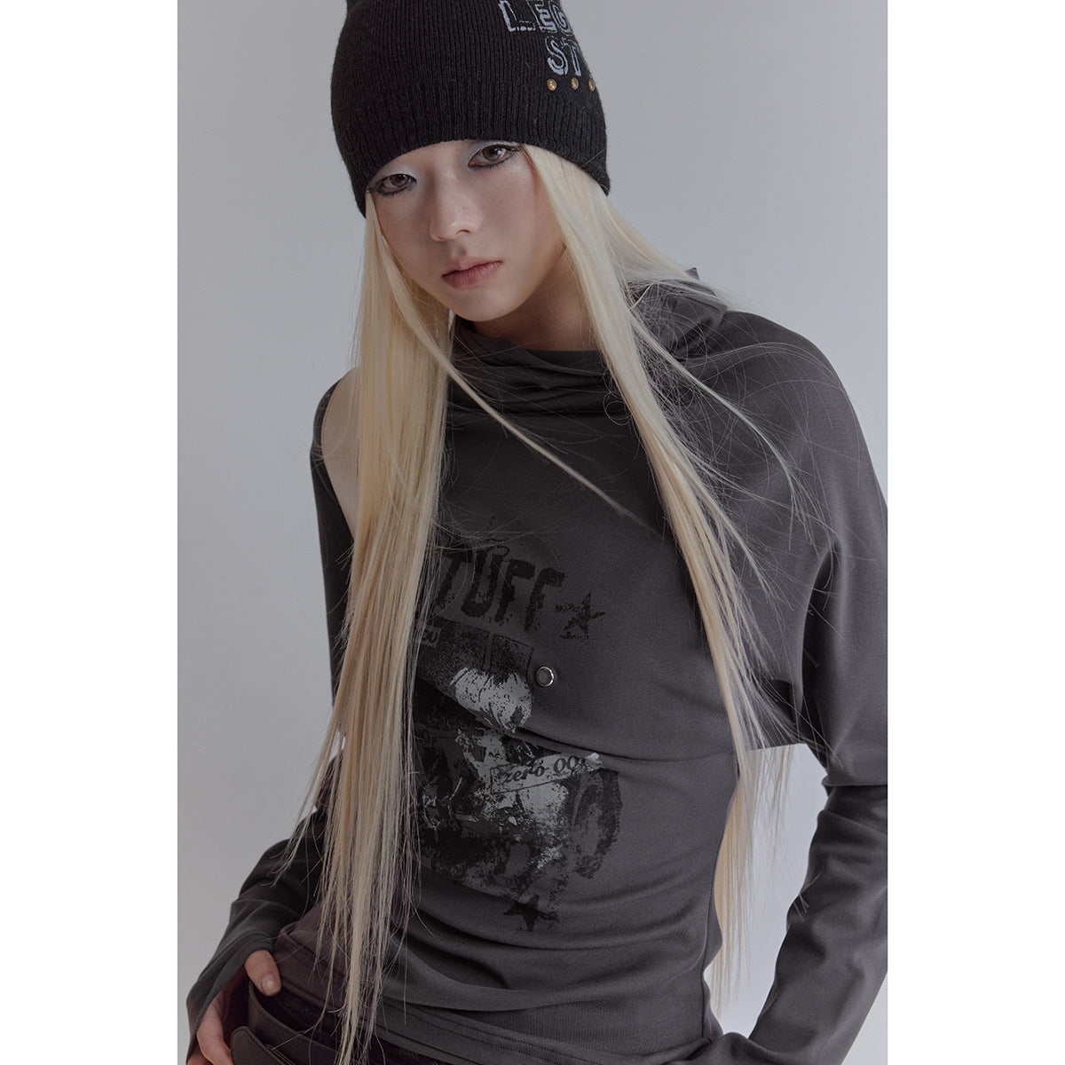 Close view of a model wearing a charcoal draped long-sleeve top with a distressed black chest graphic.