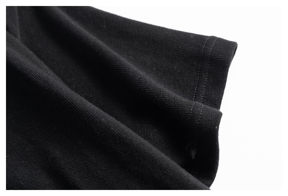 Close-up of the black knit garment's folded edge and stitched hem.