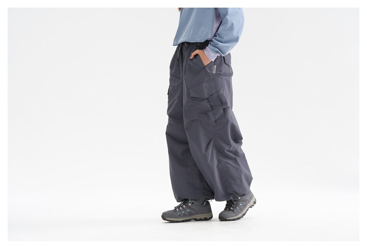 Cropped side view of a model wearing dark slate wide-leg cargo pants with flap pockets and hiking shoes.