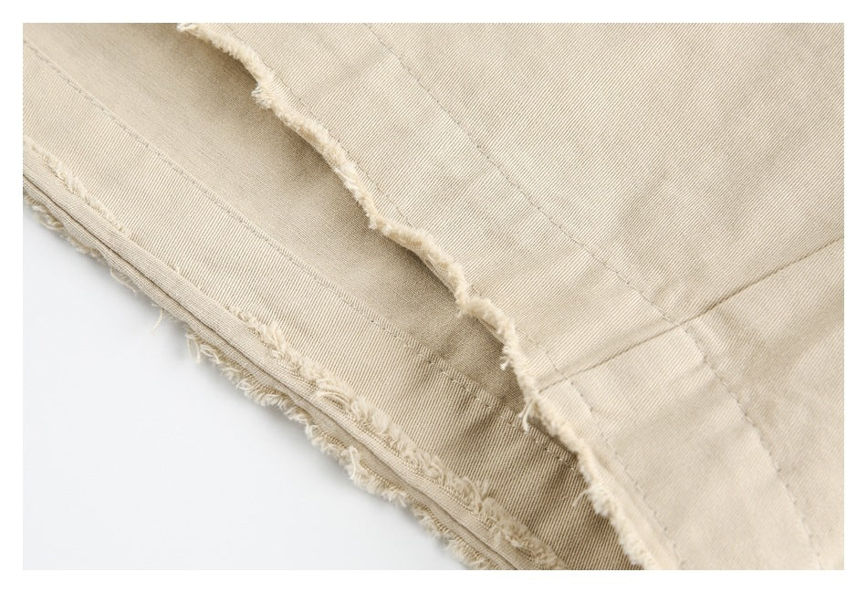 Close-up of a beige garment edge with a raw, frayed finish and stitched seams.